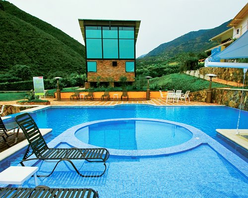 Outdoor swimming pool with chaise lounge chairs alongside the mountains.