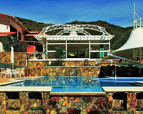 An outdoor swimming pool with patio furniture and sunshade alongside resort unit.