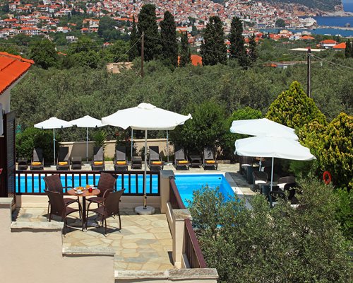 Balcony with patio alongside an outdoor swimming pool with chaise lounge chairs and sunshades.