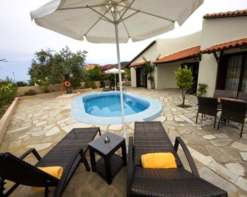 An outdoor hot tub with chaise lounge chairs and sunshades alongside resort units.