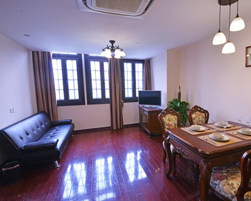 A well furnished living room with a television and wooden dining table.