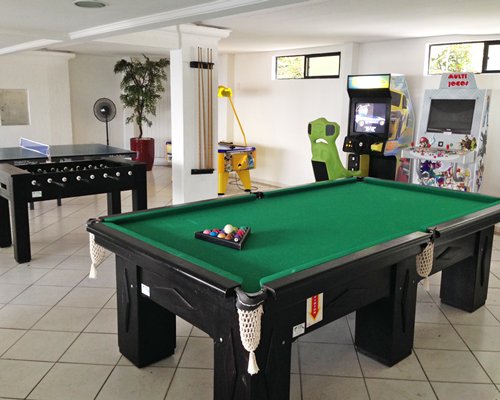 An indoor recreational room with a pool table foosball table ping pong and arcade games.