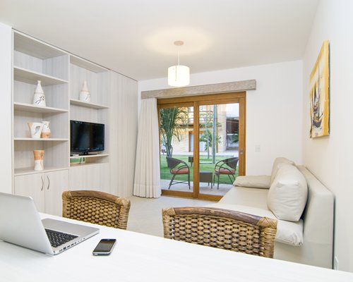 A well furnished living room with a television laptop and patio.