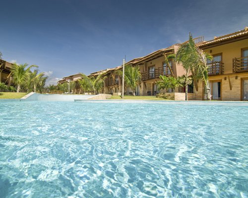 Large outdoor swimming pool with palm trees alongside multiple unit balconies.