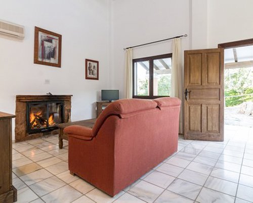 A well furnished living room with a television fire in the fireplace and patio.