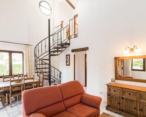 A living room with a dining area and spiral staircase.