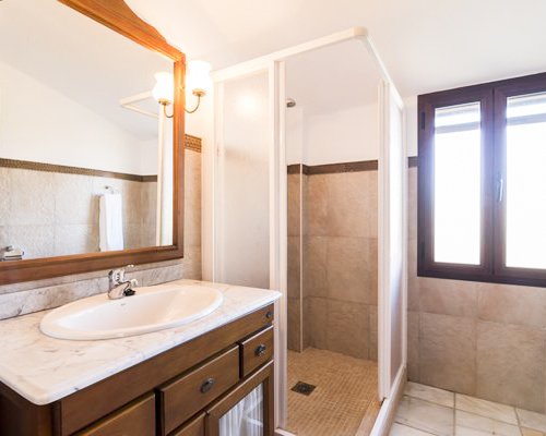 A bathroom with a shower stall and single sink vanity.