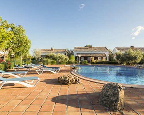 An outdoor swimming pool with chaise lounge chairs and landscaping alongside multiple resort units.