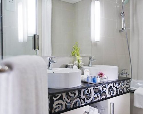A bathroom with bathtub shower and double sink vanity.