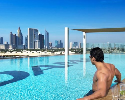 A man relaxing in an outdoor swimming pool alongside multi story resort units.