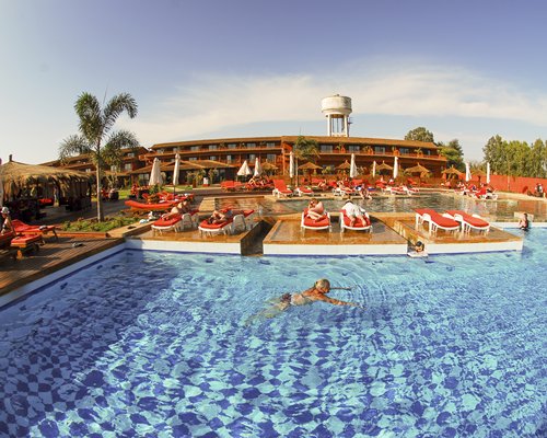An outdoor swimming pool with chaise lounge chairs and sunshades.