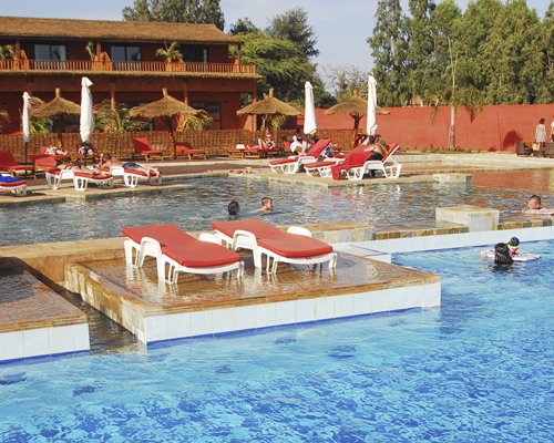 People enjoying an outdoor swimming pool with chaise lounge chairs.