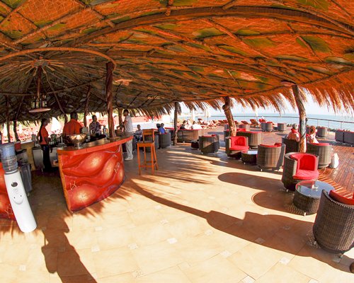 A well equipped an outdoor bar with a thatched roof.