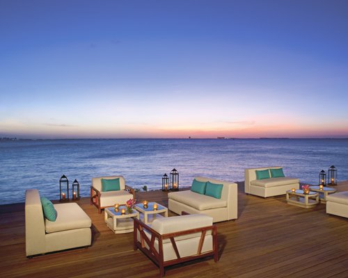An outdoor lounge area with candles lights alongside the ocean.
