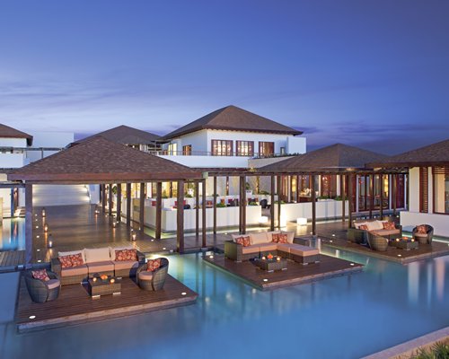 An outdoor pool with lounge access alongside multi story resort units at dusk.