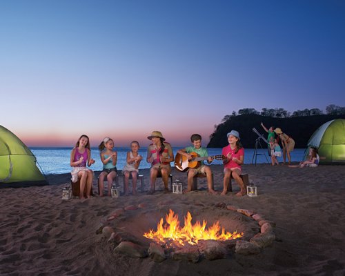 View of kids enjoying in a campfire alongside the beach.