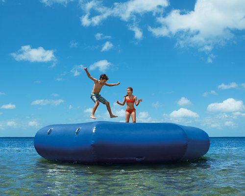 View of kids jumping into the ocean from a pool float.