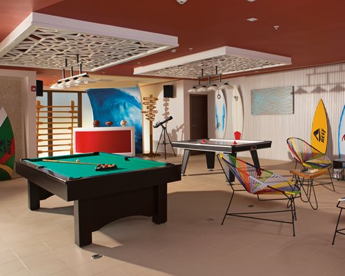 A view of air hockey and eight ball pool table in an indoor recreational room.