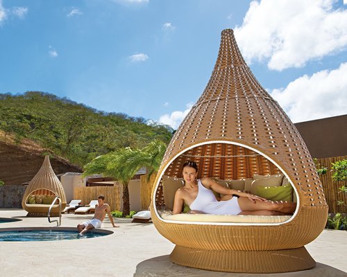 An outdoor hot tub with chaise lounge chairs and garden furniture.