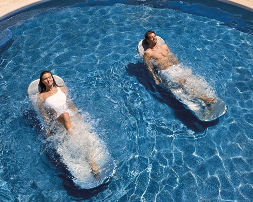 A couple relaxing in an outdoor swimming pool.