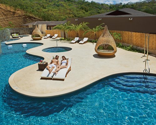 Outdoor swimming pool and hot tub with cocoon chairs.