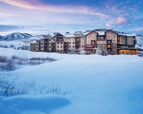AN EXTERIOR VIEW OF THE RESORT AND THE MOUNTAINS COVERED IN SNOW.