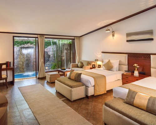 A well furnished bedroom with two double beds and a patio.