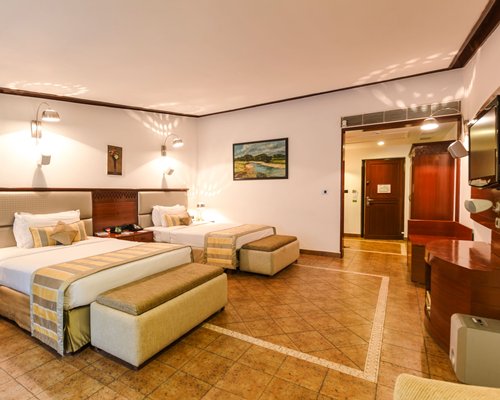 A well furnished bedroom with two beds and a television.