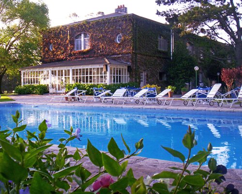 An outdoor swimming pool with chaise lounge chairs alongside a multi story resort unit.