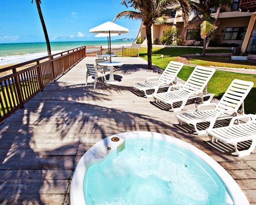 An outdoor hot tub with chaise lounge chairs alongside the beach.