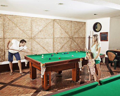 A family in the indoor recreation room with pool tables.