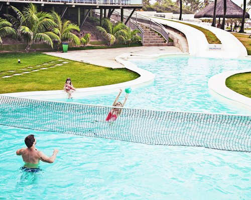 A family playing volleyball at an outdoor swimming pool.