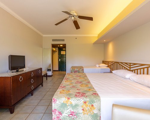 A well furnished living room with a television and dining area alongside bedroom.