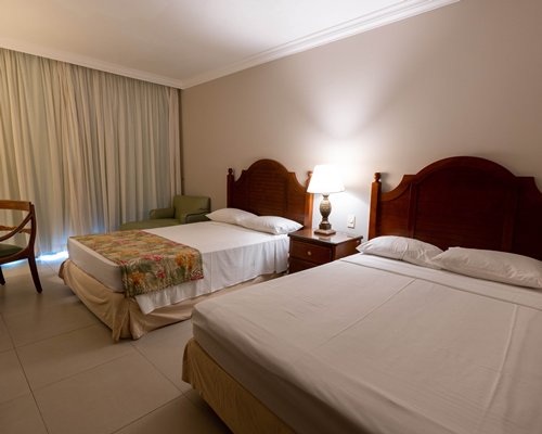 A well furnished bedroom with queen bed and balcony.
