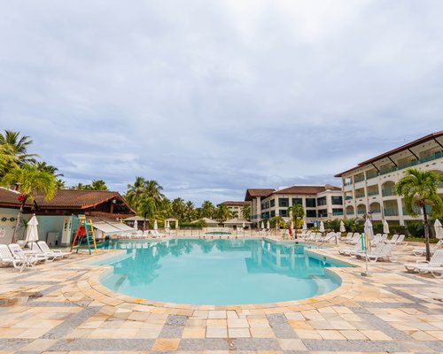 An outdoor swimming pool with chaise lounge chairs and sunshades.