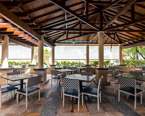 An outdoor swimming pool with chaise lounge chairs sunshades and pool volleyball net surrounded by trees.