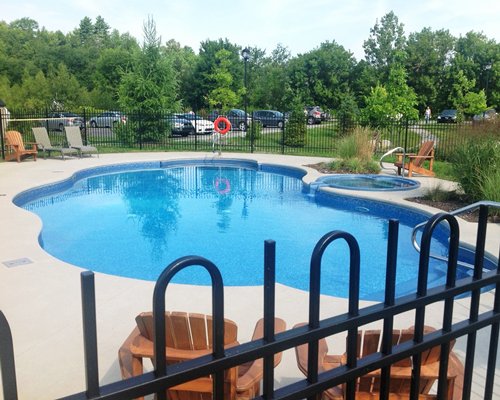 An outdoor swimming pool with a hot tub and chaise lounge chairs.