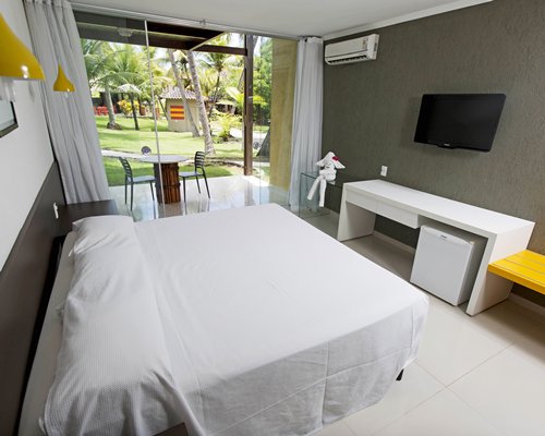 A well furnished bedroom with a queen bed television and patio.