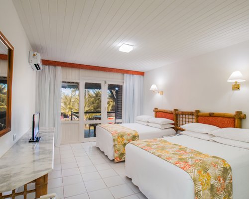 A well furnished bedroom with two beds and a television.