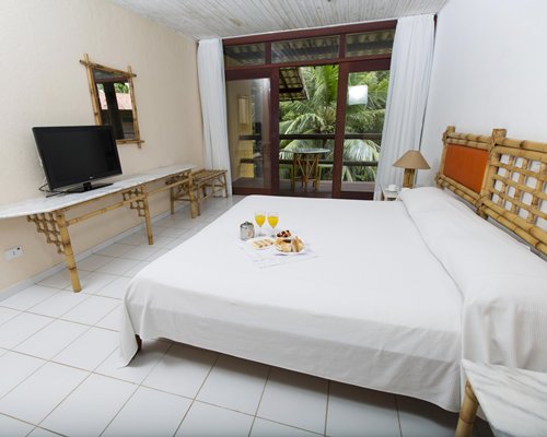 A well furnished bedroom with a queen bed and television.