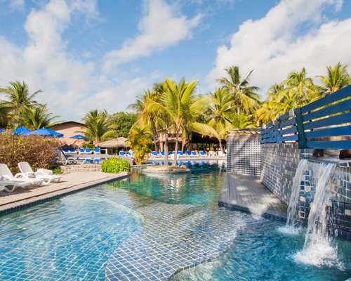An outdoor swimming pool with chaise lounge chairs sunshades and the water curtain.