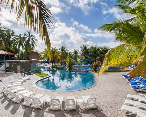 An outdoor swimming pool with chaise lounge chairs and sunshades.