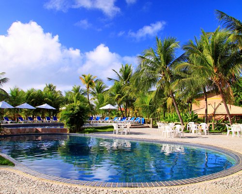 An outdoor swimming pool with chaise lounge chairs sunshades and patio furniture.