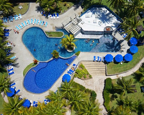 An aerial view of a swimming pool with chaise lounge chairs and sunshades.