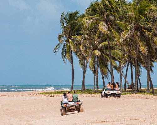 Group of people riding ATVs at the beach.