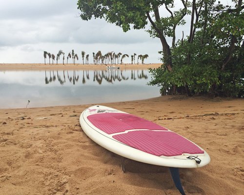 A paddle board on the beach alongside the ocean.