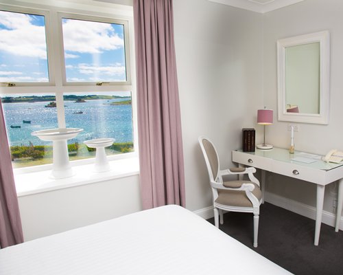 A well furnished bedroom with a dresser and the beach view.