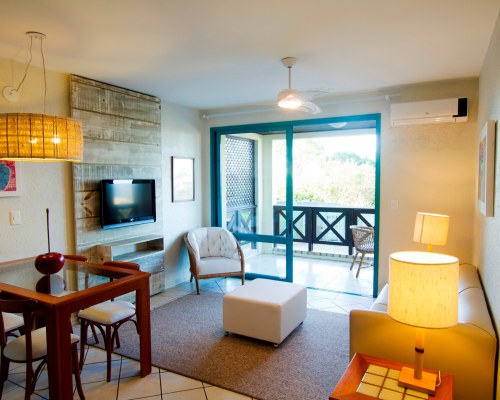 A WELL FURNISHED LIVING ROOM WITH A TELEVISION DINING AREA AND BALCONY.