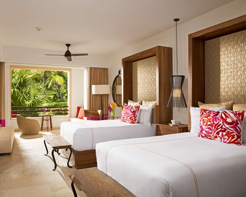 A well furnished bedroom with two beds and balcony.