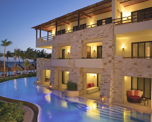 An exterior view of the multi story resort balconies alongside the outdoor swimming pool at night.